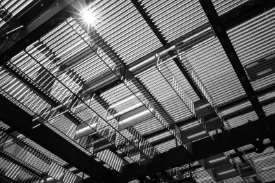Schwarz-Weiß Aufnahme. Zeigt die aus Plastik bestehende, lichtdurchlässige Deckenkonstruktion im Innenraum eines Veranstaltungsraumes, durch den die strahlende Sonne zu sehen ist.
