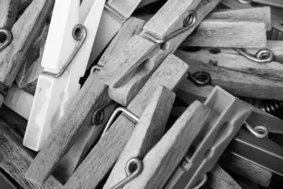 Schwarz-Weiß Aufnahme; zeigt eine Nahaufnahme von Wäscheklammern, wobei die meisten aus Holz bestehen und nur eine aus Plastik.